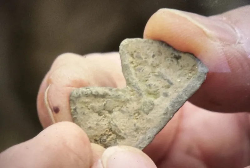 Cap Badge Fragment (Money Pit Dunfield spoils) — Colonial Artifact found at Oak Island, Oak Island, Nova Scotia. Dated: 18th century